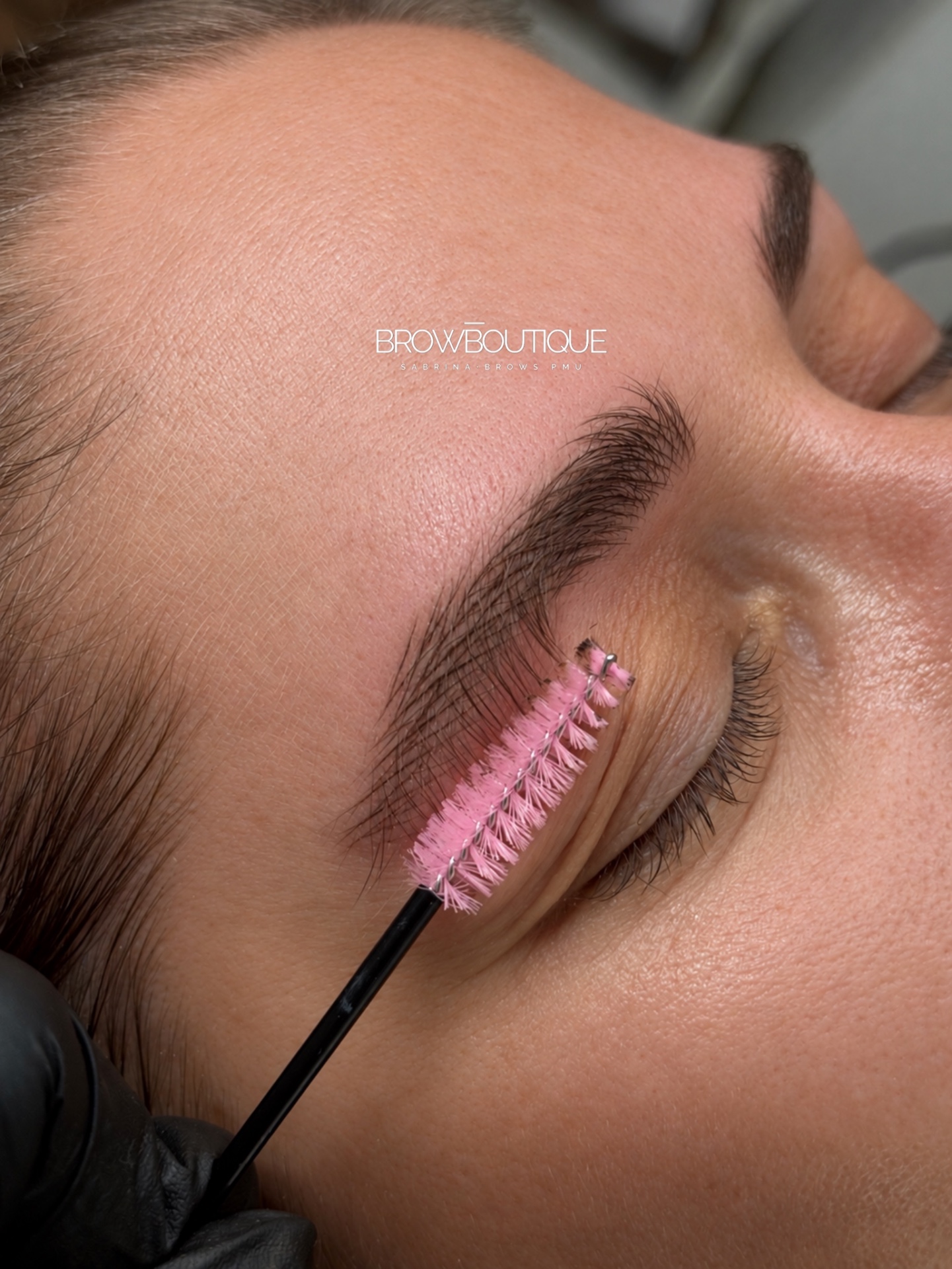 Close-up of hyperrealistic Breath Brows nano hairstrokes combed into place with a spoolie brush immediately after treatment, in the Cascais studio